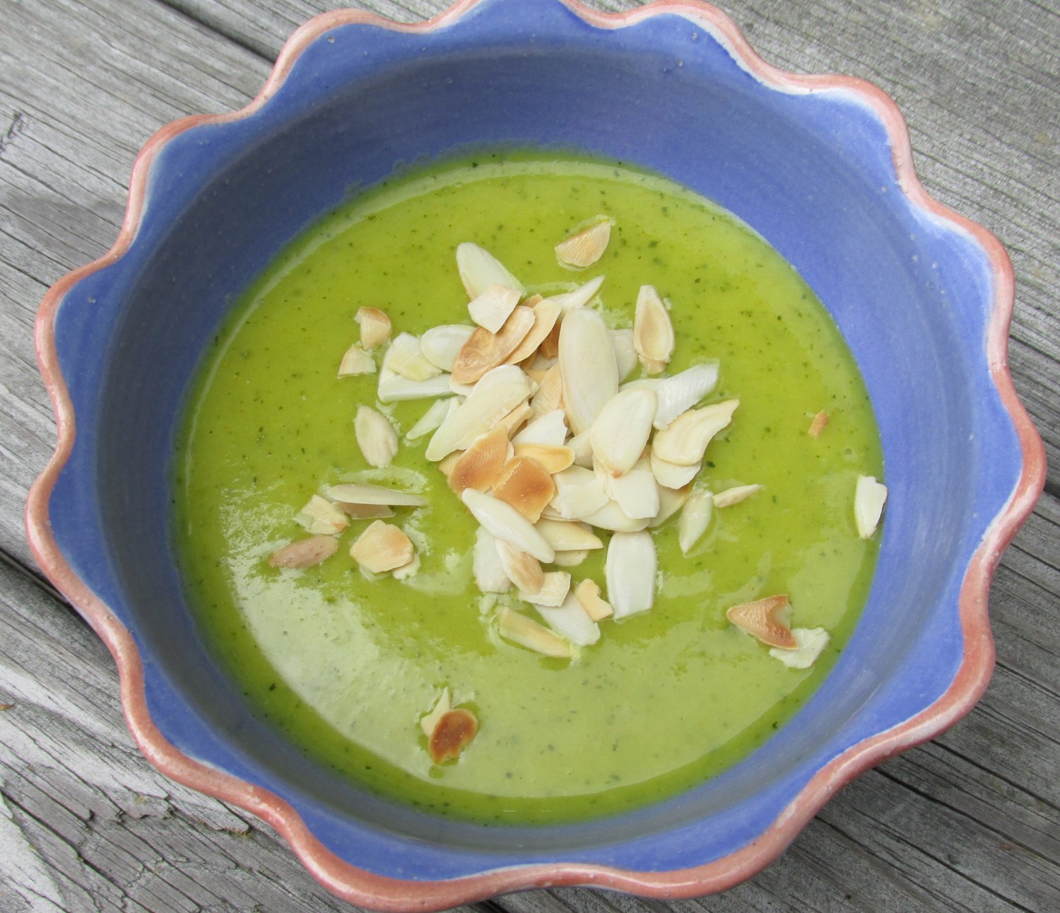 Cold zucchini soup with curry, garnished with toasted silvered almonds.